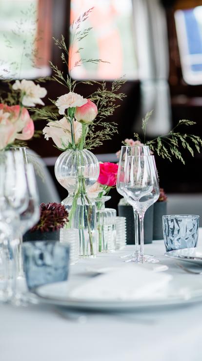 Table dressée élégante avec fleurs roses, verres à vin et nappe blanche dans un restaurant