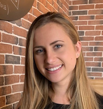 Portrait d'Ivana Houche souriante devant un mur en briques