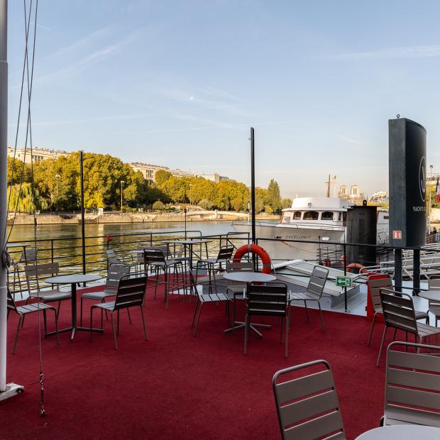 Terrasse extérieure d'un yacht sur la Seine à Paris, tables et chaises métal, moquette rouge