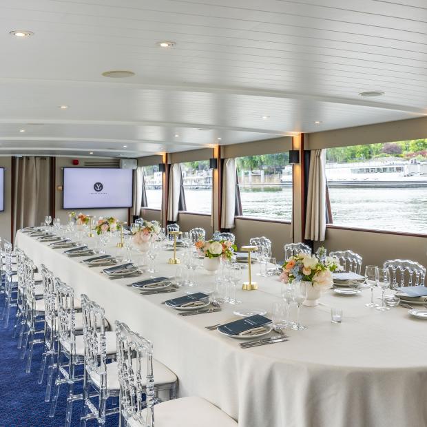 Salle de banquet Yachts de Paris avec grande table dressée sur la Seine