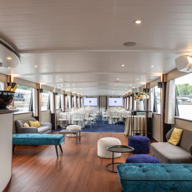 Salle événementielle luxueuse à bord du yacht Victoria à Paris, avec tables dressées et lounge