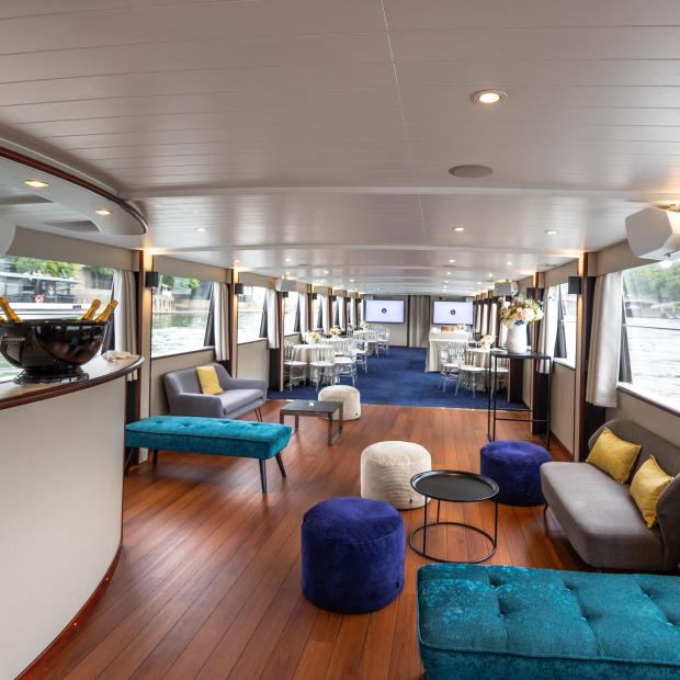 Salon intérieur luxueux d'un yacht à Paris avec canapés, bar et champagne